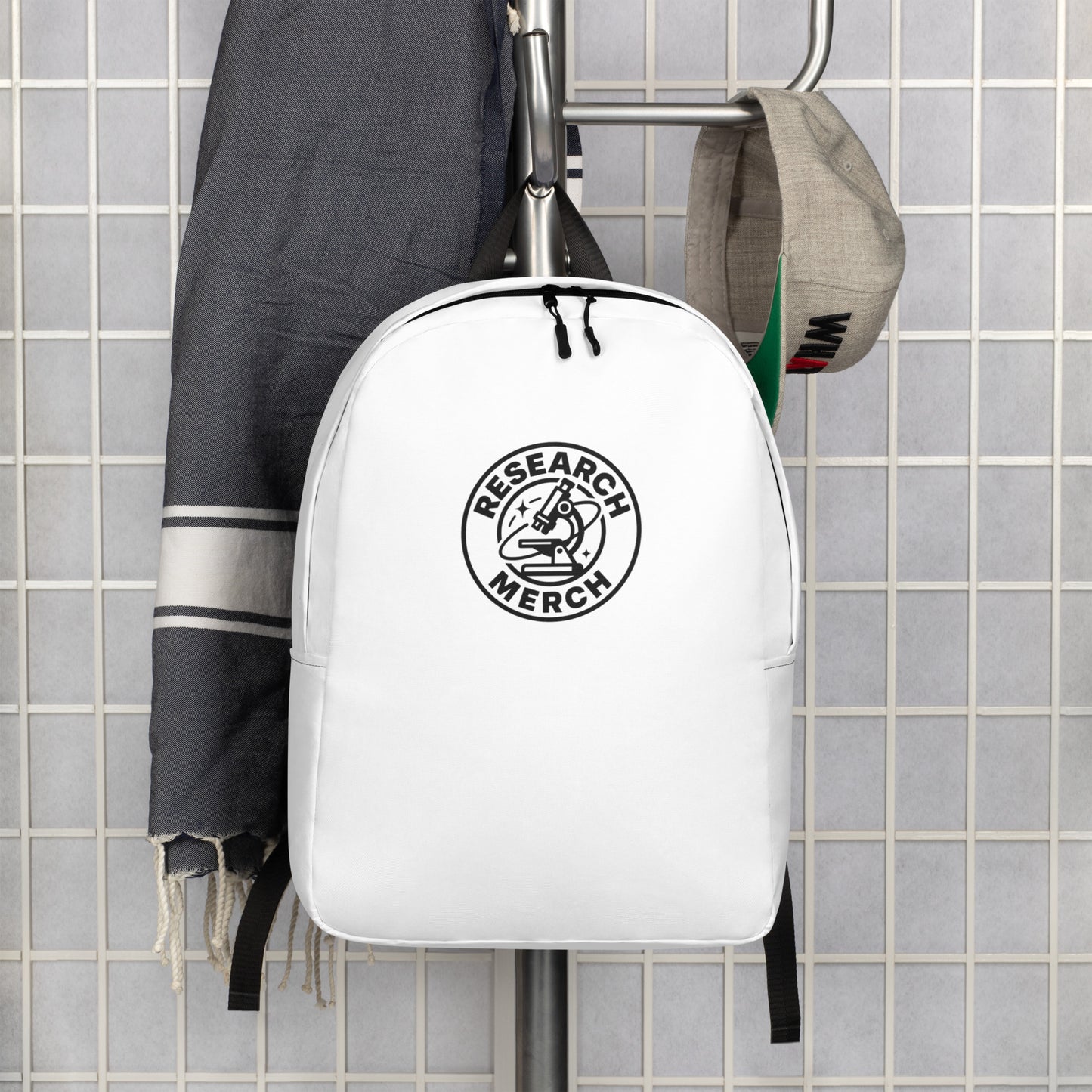 Minimalistischer weißer Research Merch Rucksack mit Logo, aufgehängt an einer Garderobe – ideal für Alltag, Reisen und Arbeit.
